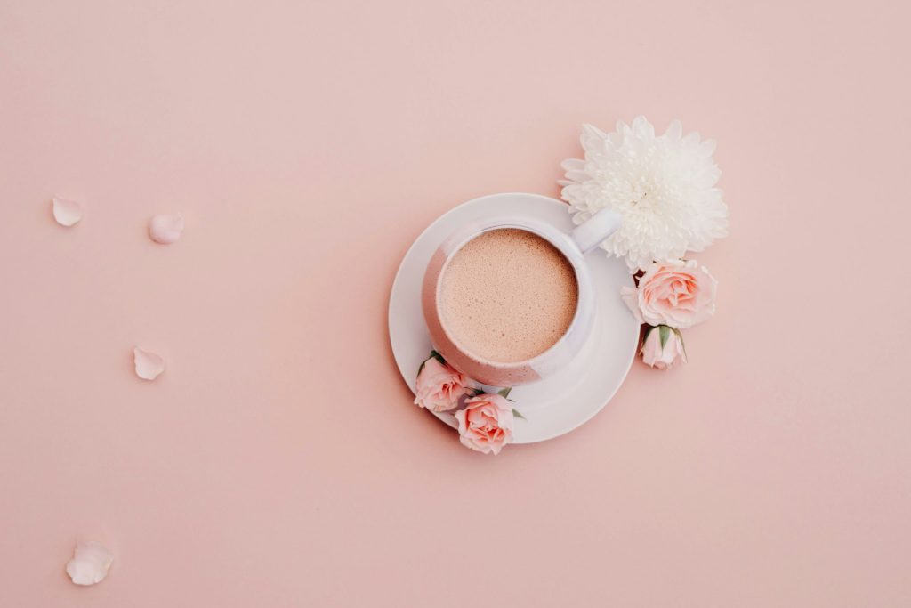 white glazed cup with saucer on pink surface