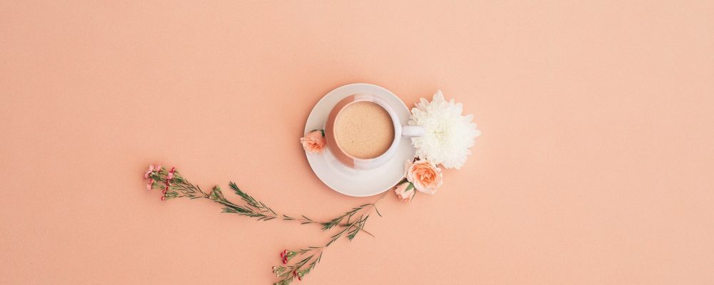 a cup of coffee on a saucer next to flowers